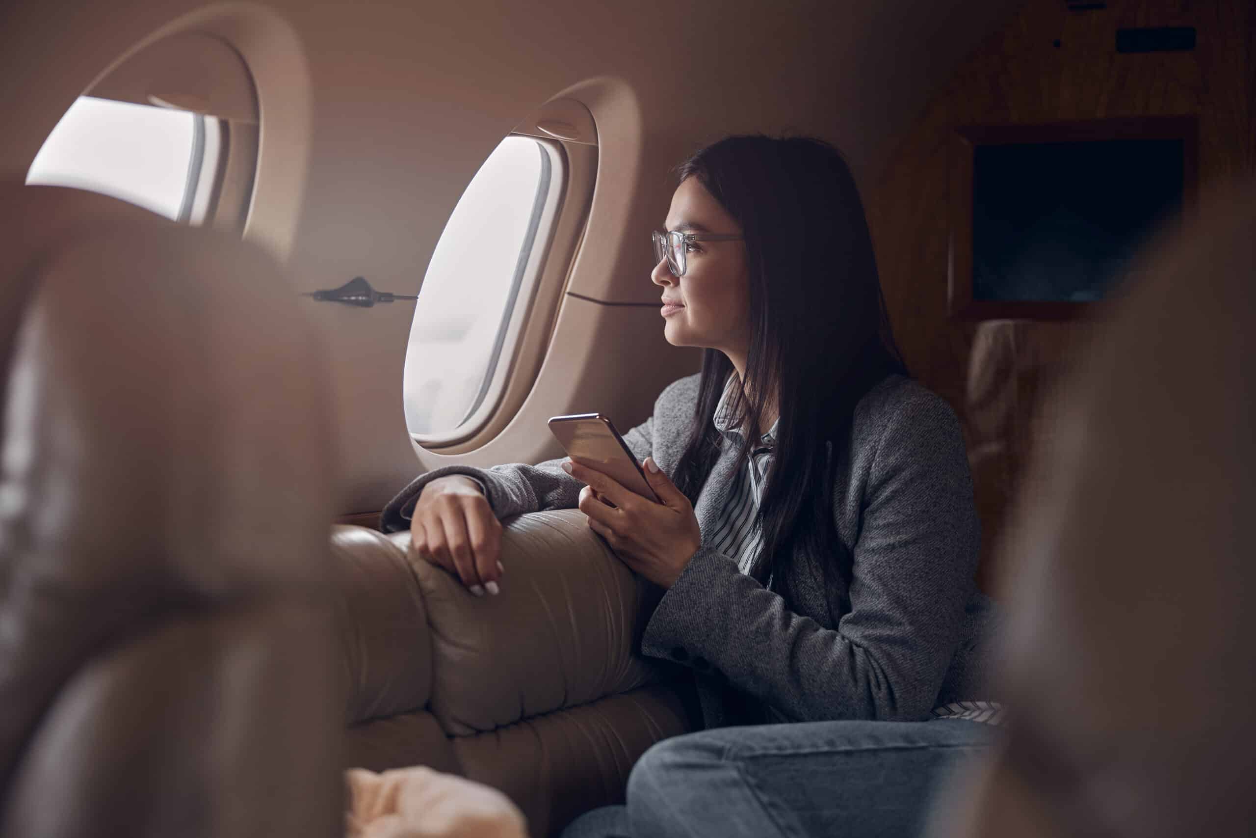 Chica sentada en el interior del avión mirando por la ventana